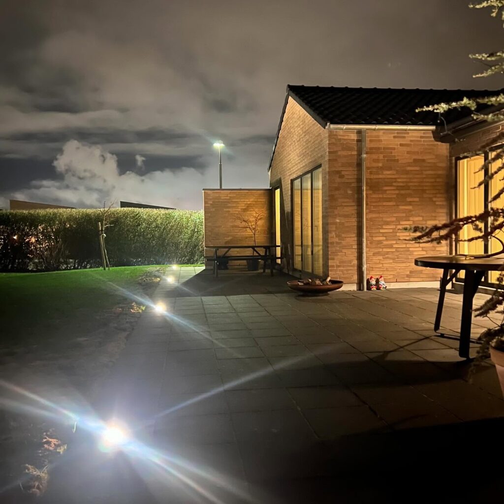 Oplyst terrasse ved murstenshus om natten
