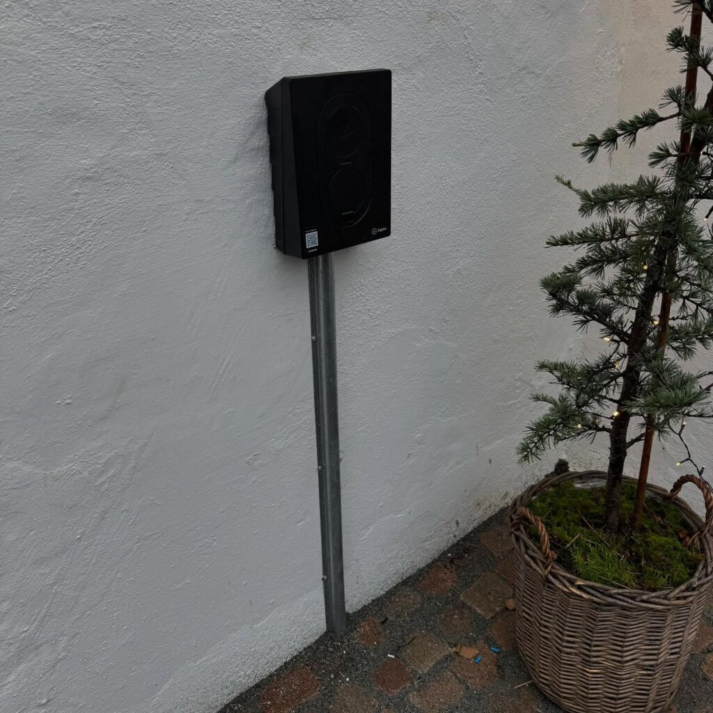 Sort elbil-ladestander ved hvid mur